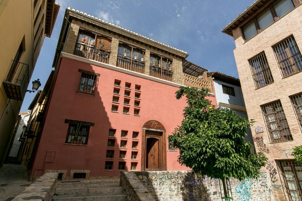 a red building with a door and a balcony at Charming Andalusian House in Granada