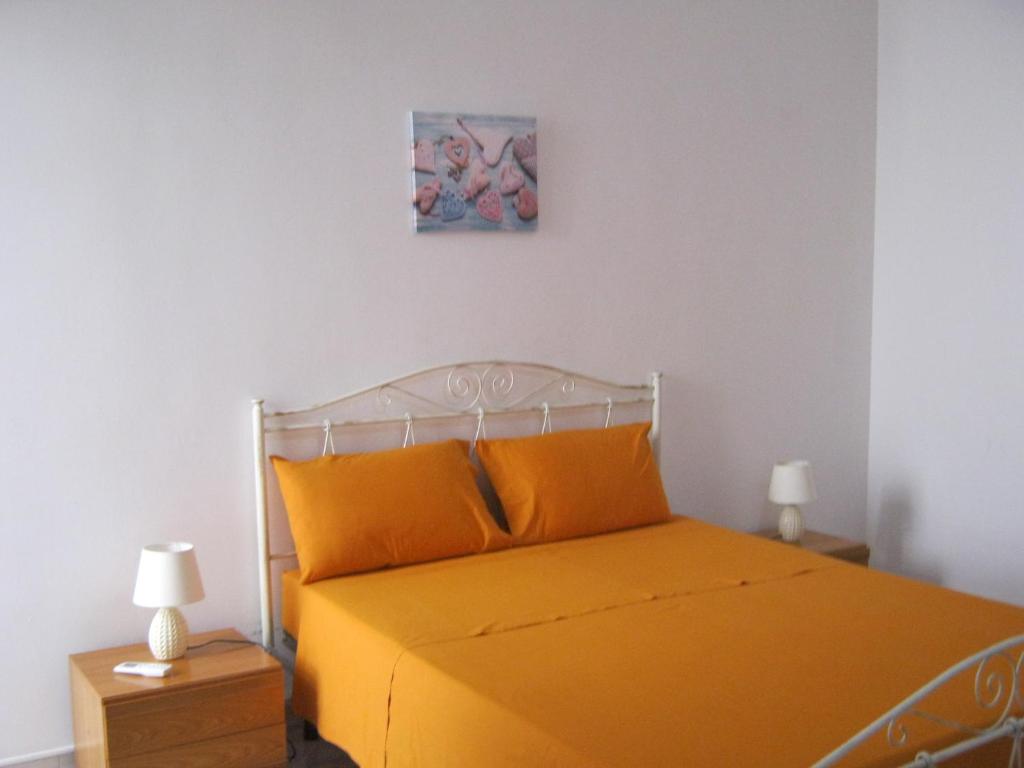 ein Bett mit einer orangefarbenen Tagesdecke und einem Gemälde an der Wand in der Unterkunft Casa Giulia Salento in Porto Cesareo