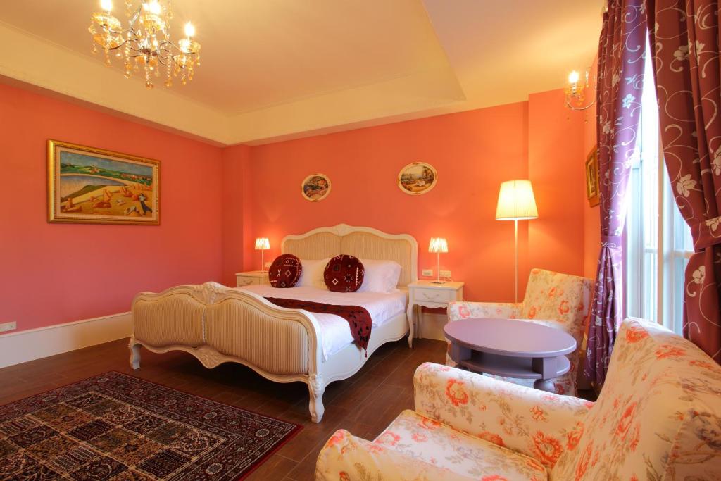 a bedroom with orange walls and a bed and chairs at Haut Rhin Villa in Zhuangwei