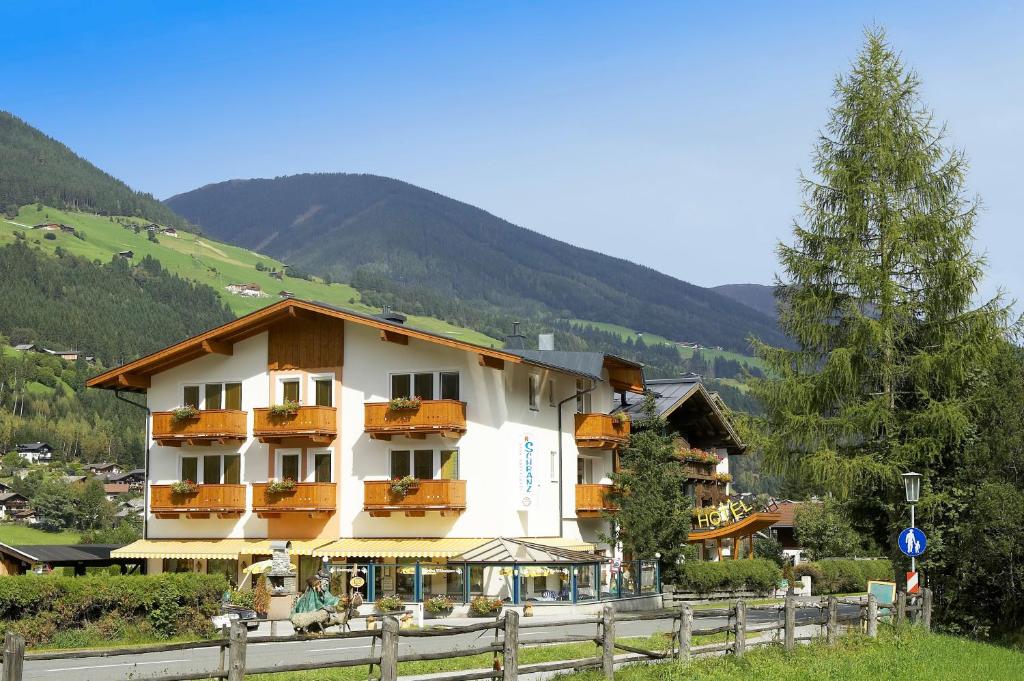 ein Gebäude mit Balkonen und einem Zaun neben einem Berg in der Unterkunft Aparthotel Garni Schranz in Wald im Pinzgau