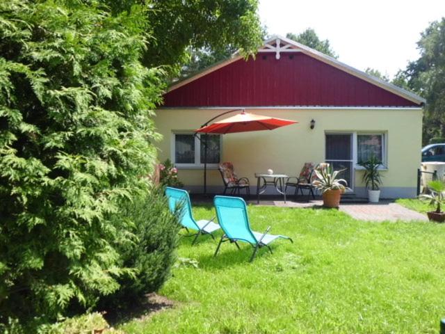 dos sillas y una sombrilla delante de una casa en Ferienhaus Ulbricht beim Senftenberger See, en Hosena
