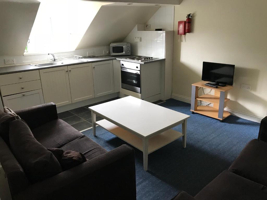 a living room with a couch and a table and a kitchen at Beach View Holiday Flats in Blackpool