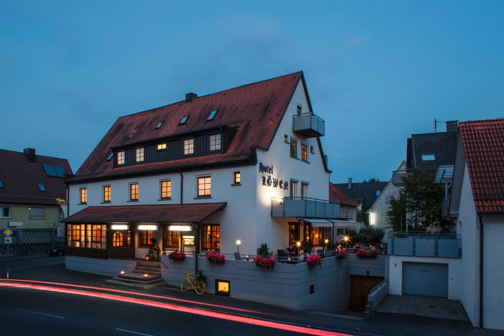 a white building with a red roof on a street at Löwen Hotel & Restaurant in Wendlingen am Neckar