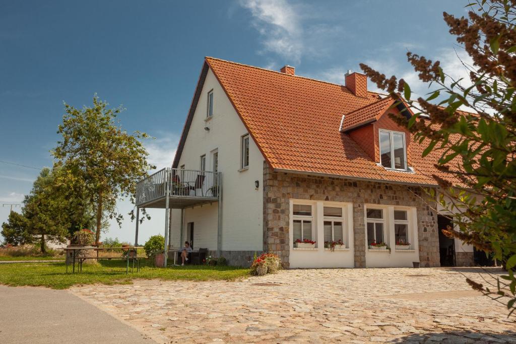 een wit huis met een oranje dak bij FEWO Reitanlage bei Altefähr in Rambin