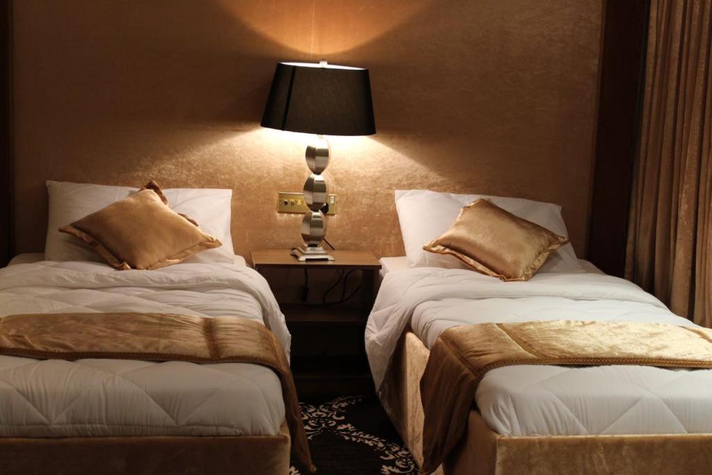 una habitación de hotel con 2 camas y una lámpara en Terrace Furnished Apartments Fintas 2, en Kuwait