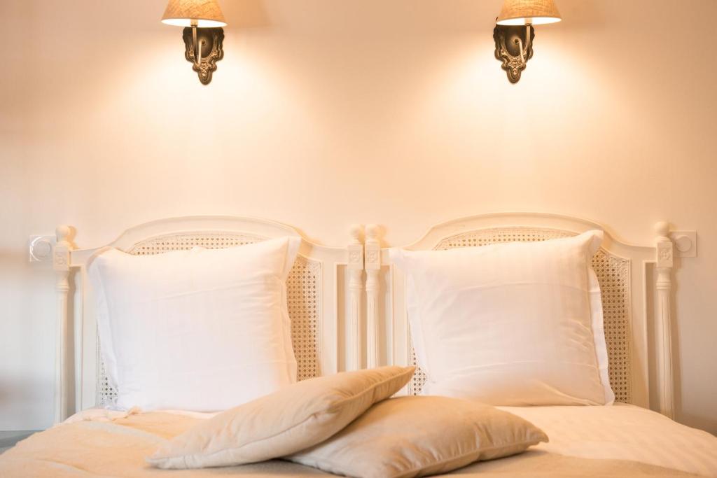 a white bed with two pillows and two lights at Les suites du 17 in Aigues-Mortes