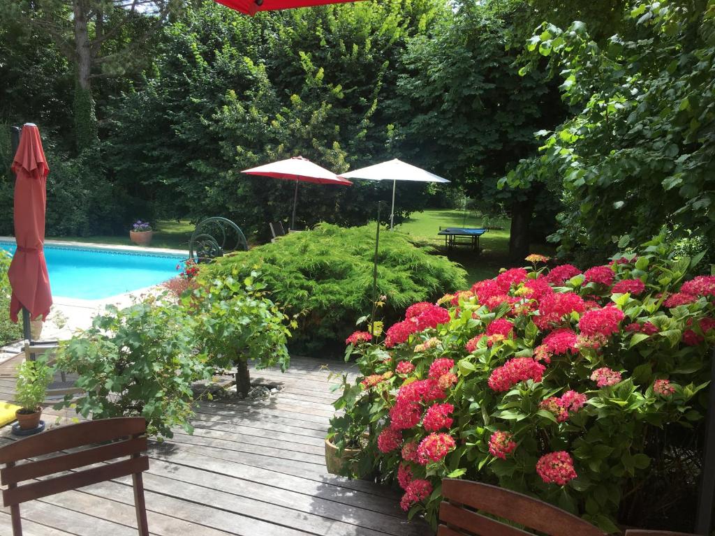 um deque de madeira com flores e uma piscina em CHAMBRES D HÔTES Chez Françoise et Michel PISCINE 4 chambres 8 lits em Chaumes-en-Brie