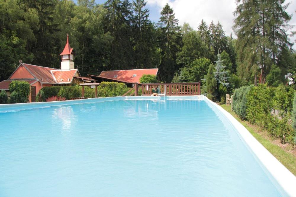 a large blue swimming pool in front of a house at Camping Karolina in Planá