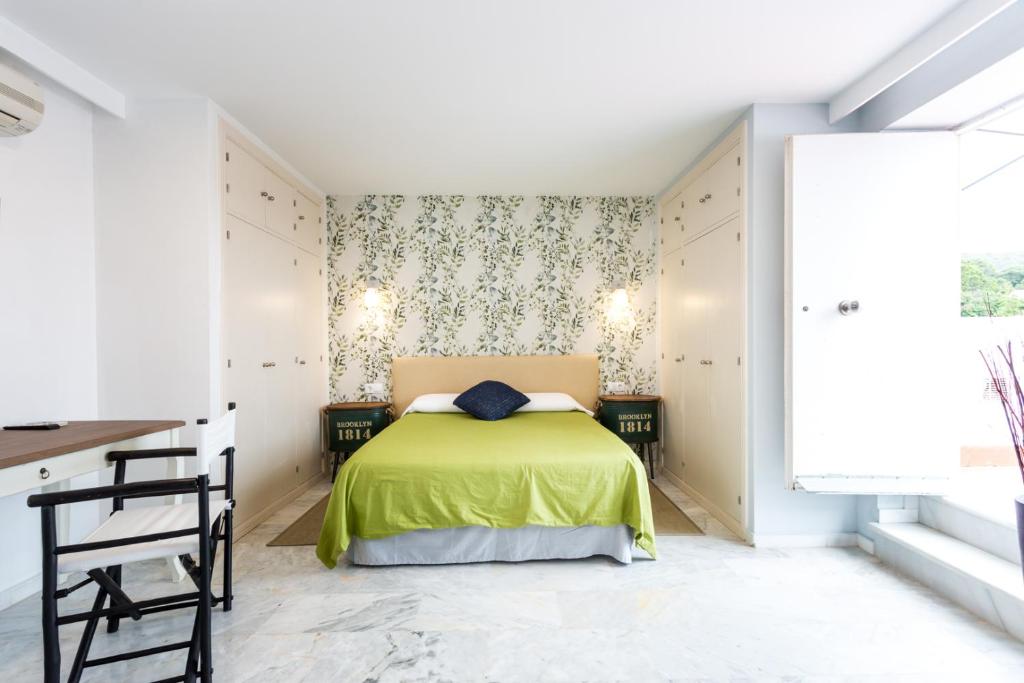 a bedroom with a green bed and a desk at Hotel Nómadas in Vejer de la Frontera