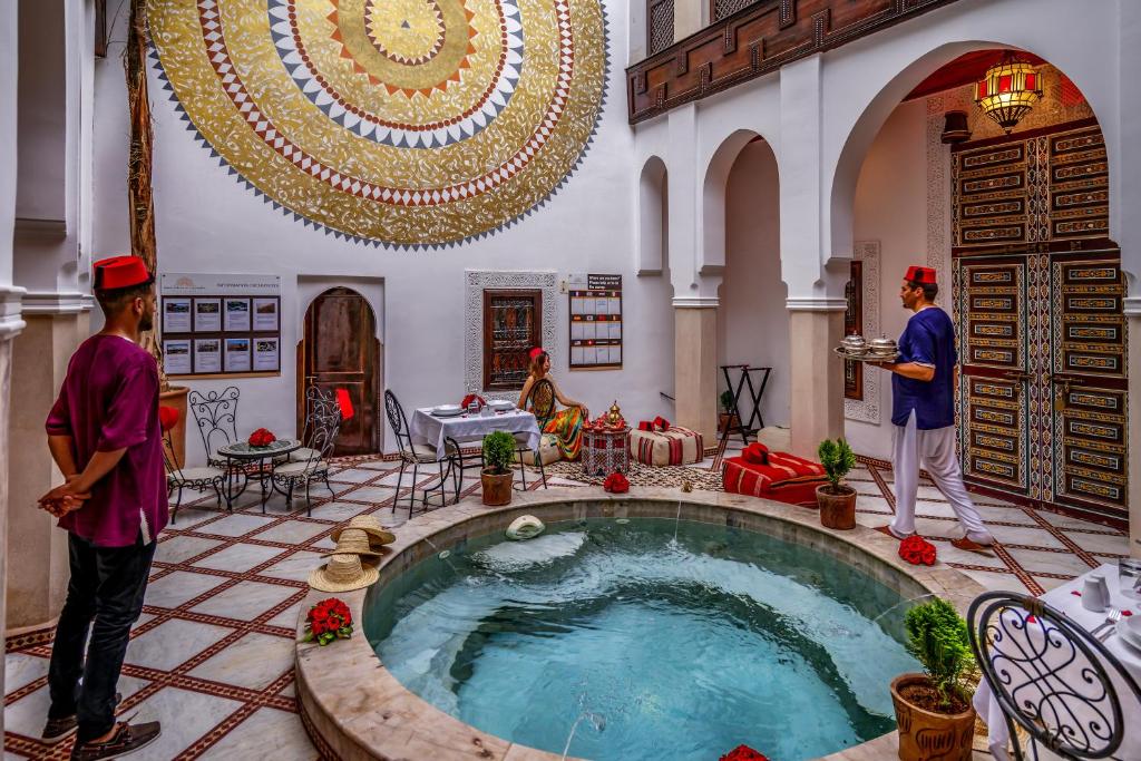 two people standing in a room with a large pool at Riad Safran et Cannelle & Spa in Marrakesh