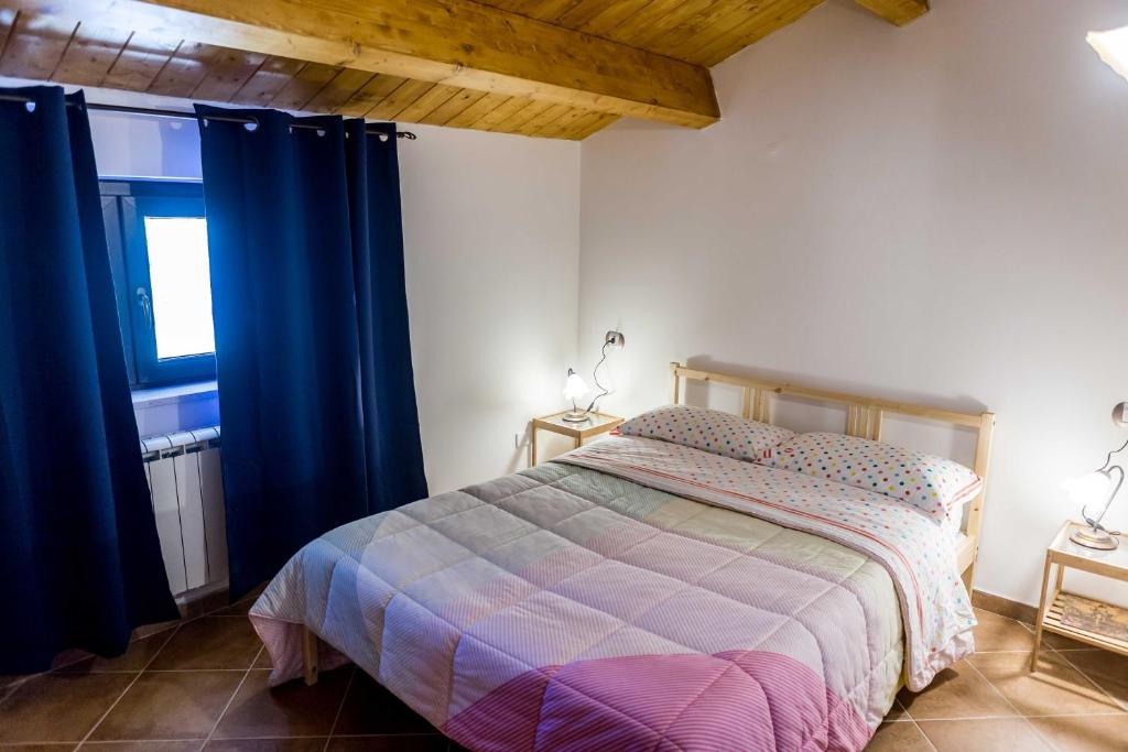 a bedroom with a bed with blue curtains and a window at La casetta al lago in Scanno