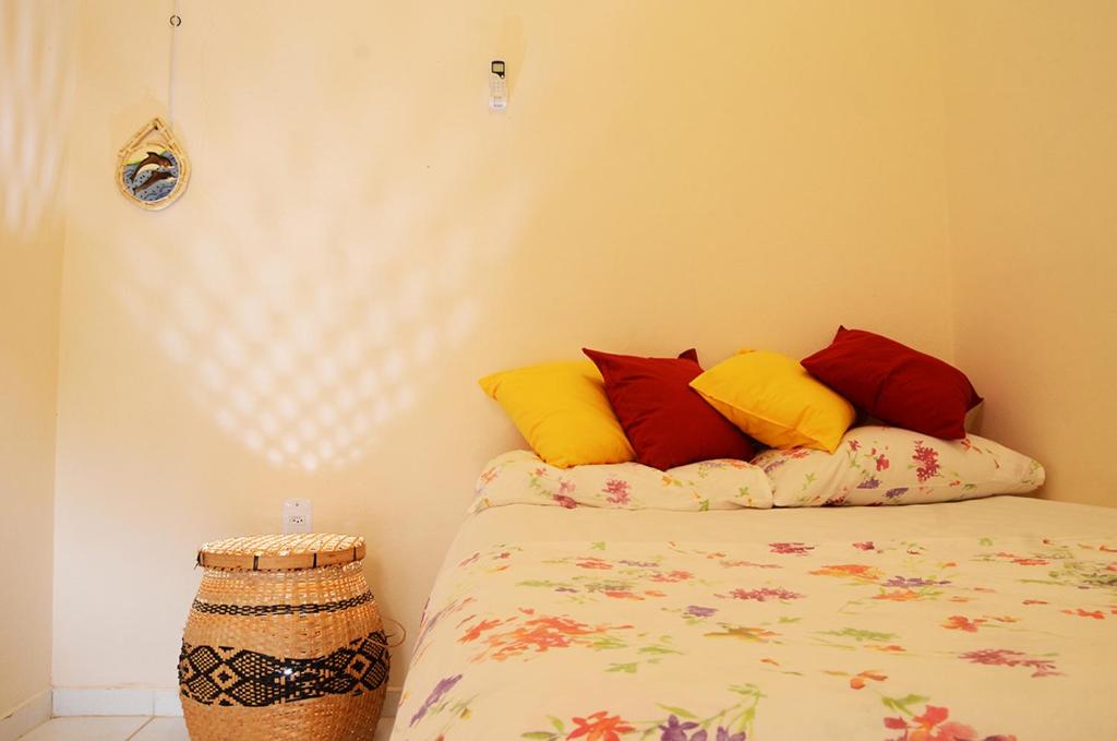 a bedroom with a bed with colorful pillows at Trindade Hospeda - Casa 4 - Cantinho do Mar in Trindade