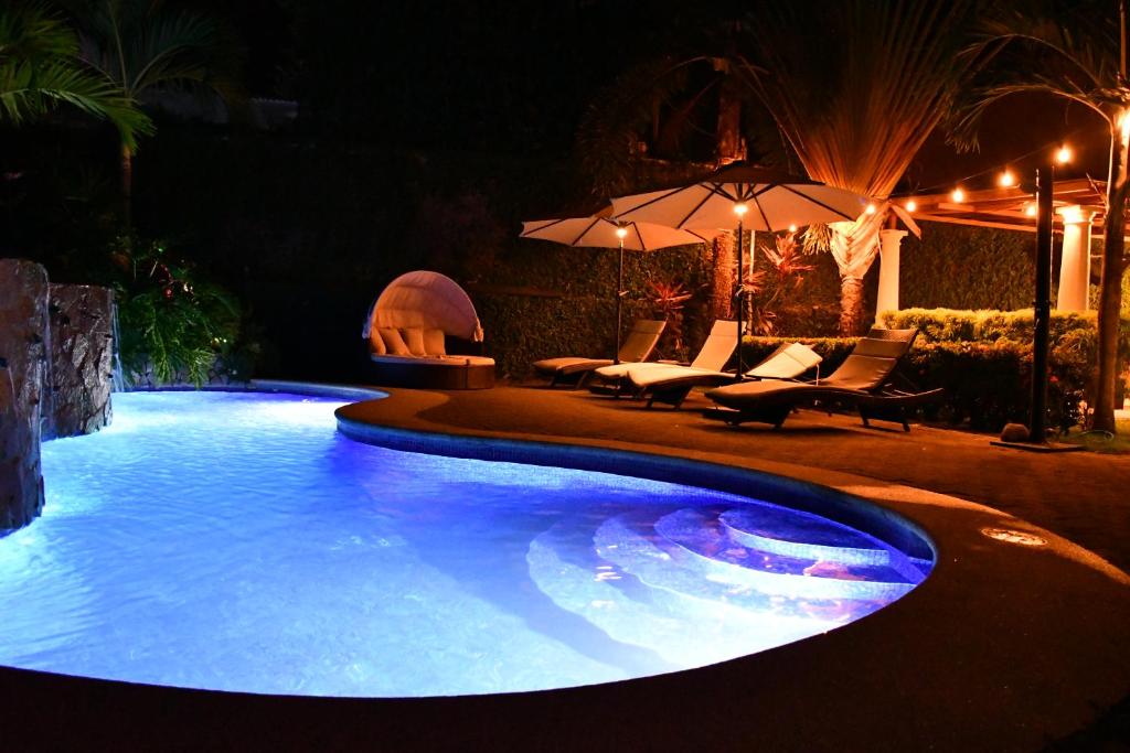 雅各的住宿－11B Jaco Sol Quadplex，夜间游泳池,配有椅子和遮阳伞