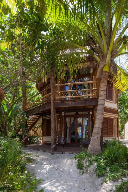 a wooden house with a palm tree in front of it at Delek Tulum in Tulum