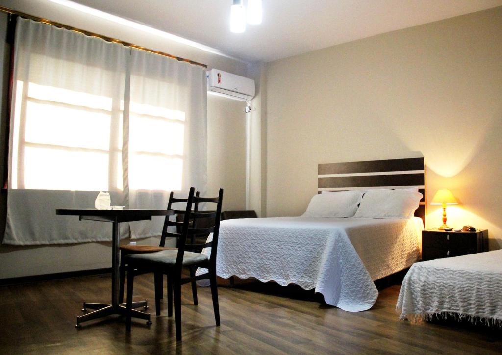 a bedroom with a bed and a table and a window at Opera Hotel in Pôrto União
