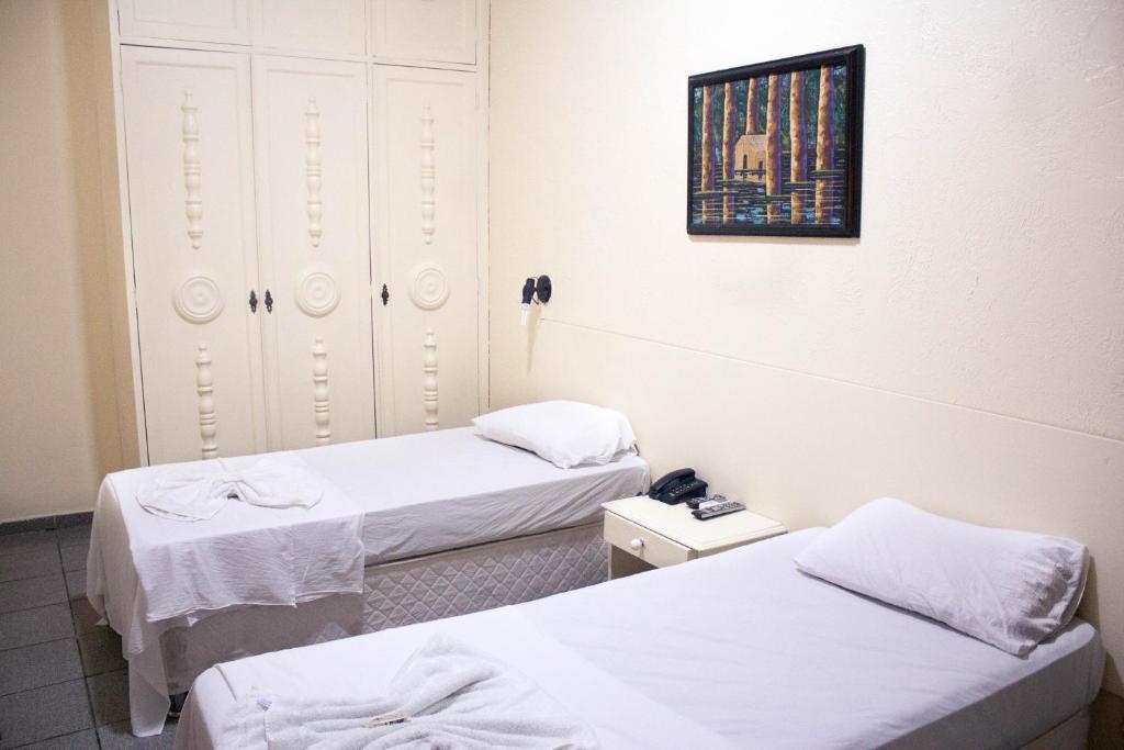 a room with two beds and a picture on the wall at Hotel Central Gold in Manaus