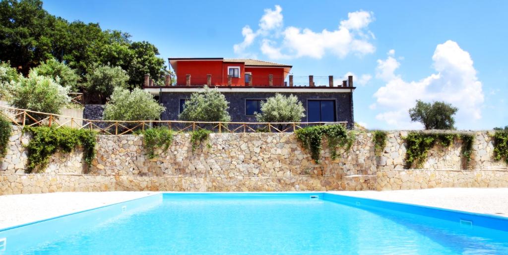 a house with a swimming pool in front of a wall at Le Oreadi in Francavilla di Sicilia