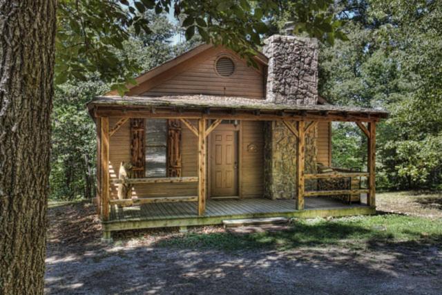 Cabaña pequeña con porche y árbol en Silver Ridge Resort en Eureka Springs