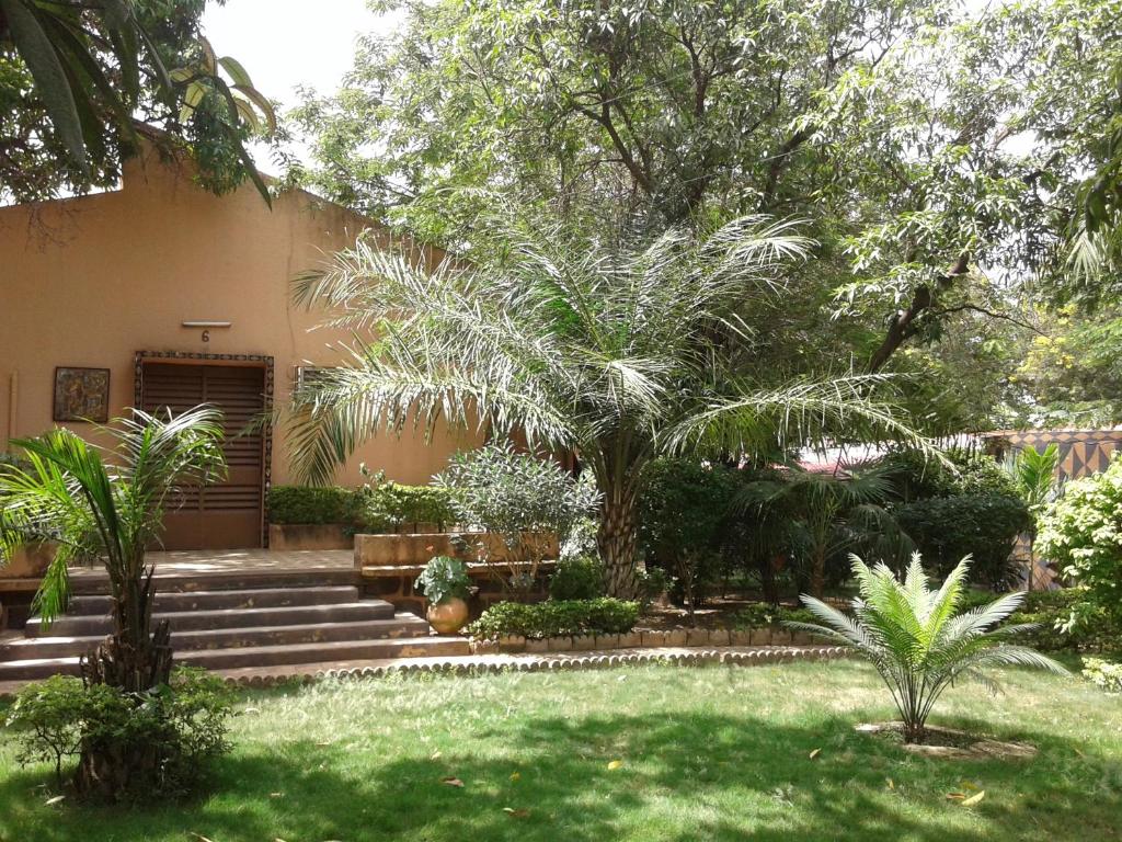 a garden with palm trees and stairs in front of a house at Hôtel Les Palmiers in Ouagadougou