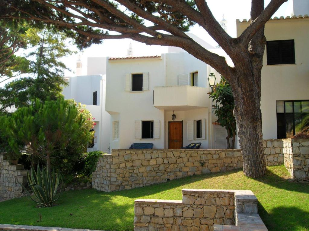 Biały dom z drzewem i kamienną ścianą w obiekcie Casa na praia e golfe w mieście Vale do Lobo