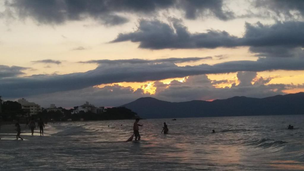 grupa ludzi na plaży o zachodzie słońca w obiekcie Condomínio Sol de Verao w mieście Florianópolis