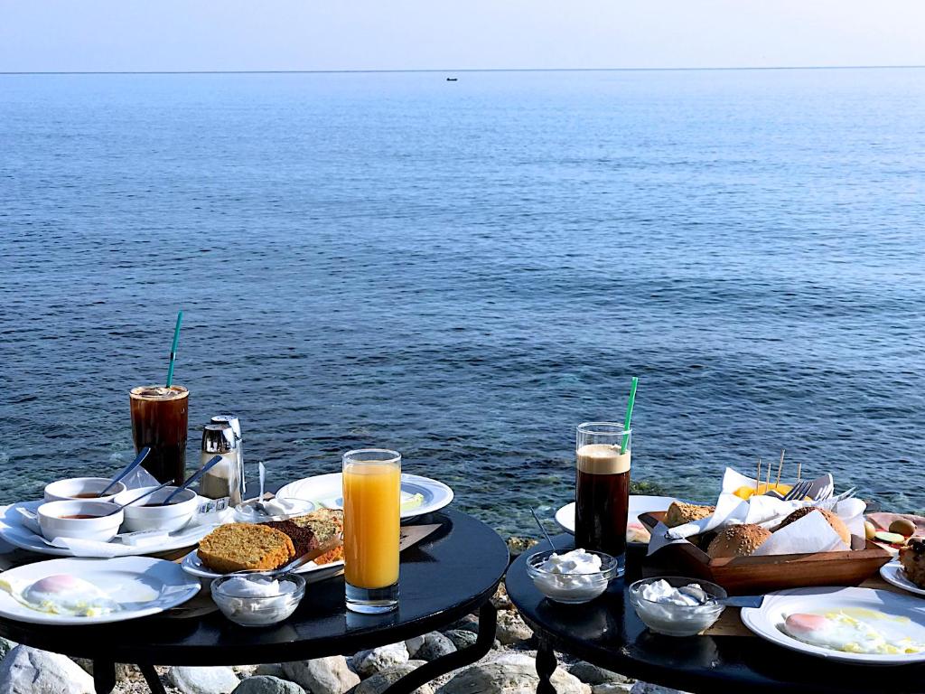 einen Tisch mit Speisen und Getränken neben dem Wasser in der Unterkunft Pansion Martha in Agios Ioannis