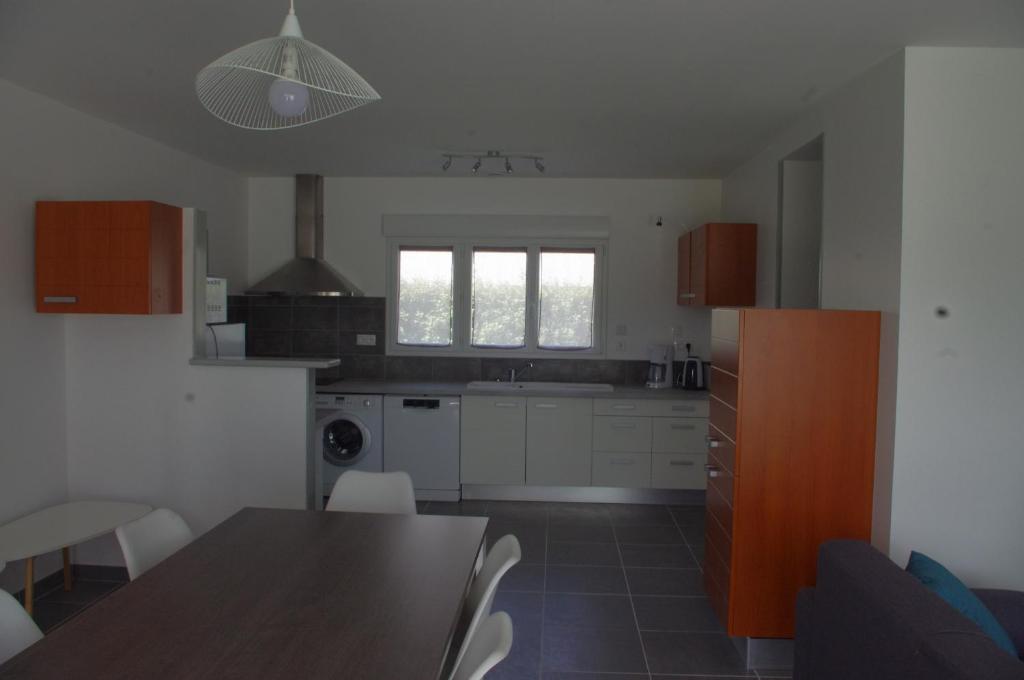 Una cocina con gabinetes blancos y una mesa y sillas. en La Maison Oceane, en Dolus d'Oléron