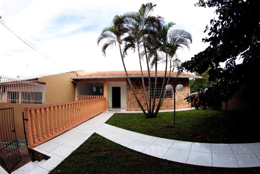 a house with a fence and palm trees in the yard at Casa com varanda próximo da Natureza in Foz do Iguaçu