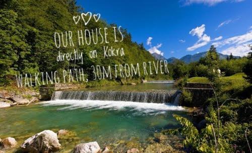 a waterfall with a sign that reads our house is exactly on top of a river at River Cave Apartment Slovenia in Visoko