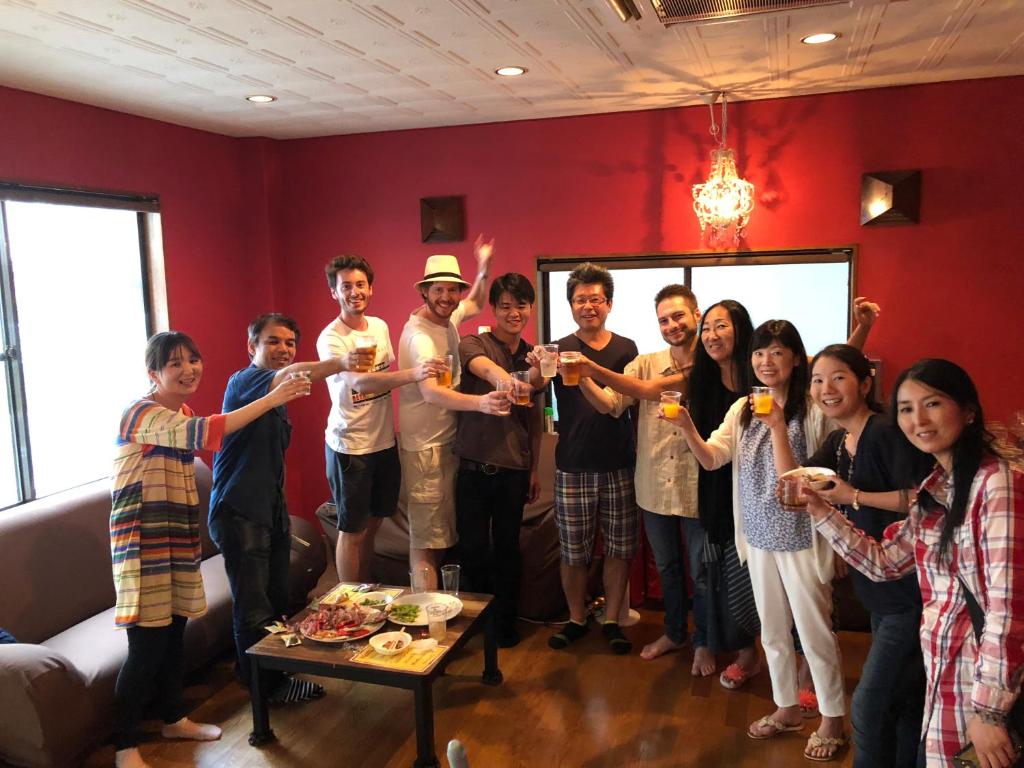 een groep mensen die in een woonkamer staan met drankjes bij HappyCloset&WasamonHostel in Kumamoto