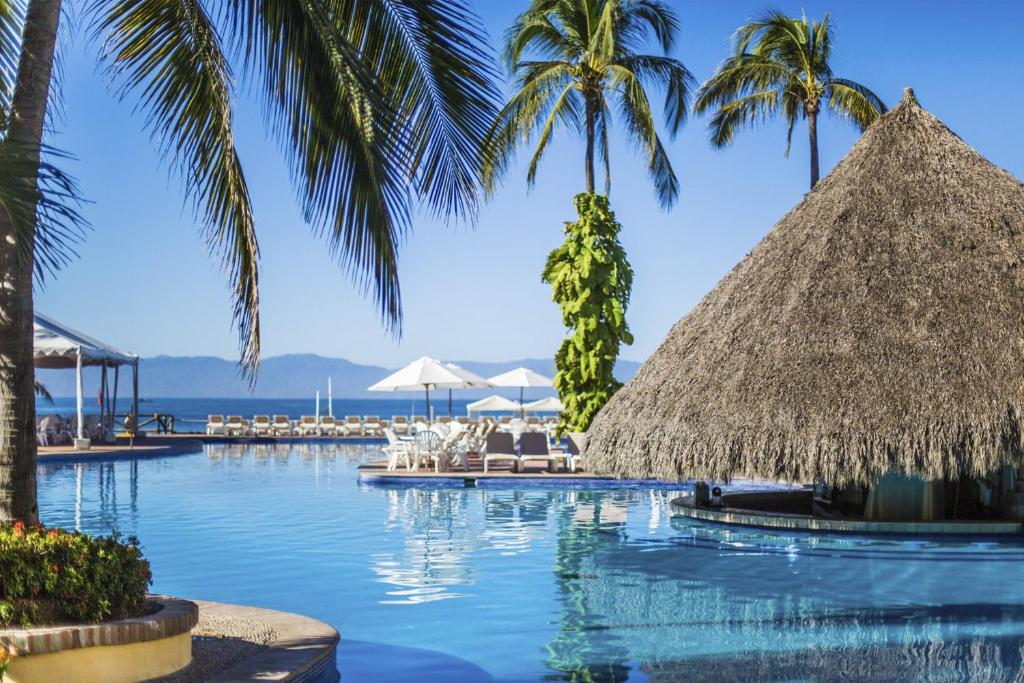 a swimming pool with palm trees and a resort at Velas Vallarta Suite Resort All-Inclusive in Puerto Vallarta