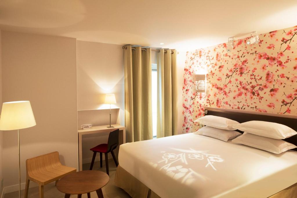 a bedroom with a bed, desk, chair and lamp at Hotel Eden in Paris