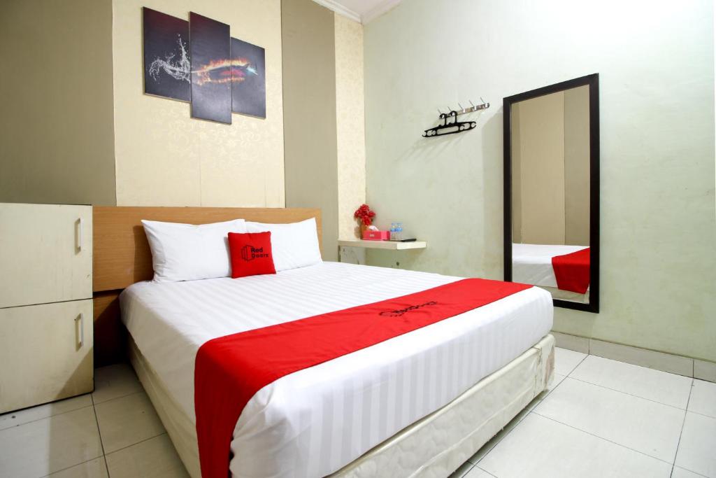 ジョグジャカルタにあるRedDoorz near Adisucipto Airport 3の大きなベッドと鏡のある寝室