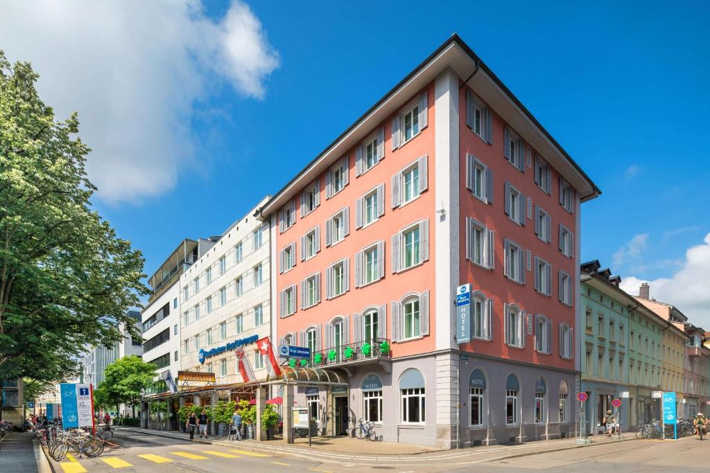 un edificio alto rojo en una calle de la ciudad en Hotel Wartmann am Bahnhof, en Winterthur