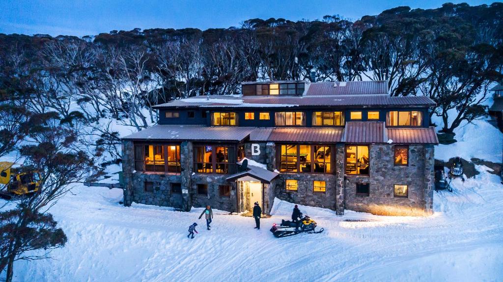 une maison dans la neige avec des gens devant elle dans l'établissement Boonoona Ski Lodge, à Perisher Valley