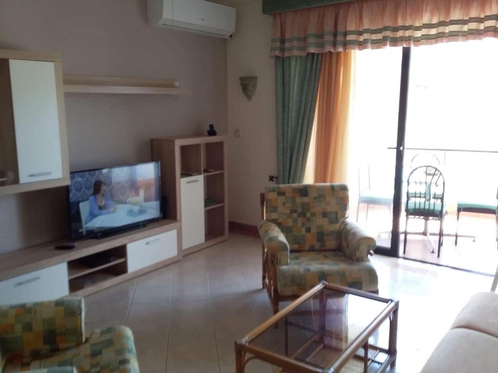 uma sala de estar com uma televisão e um sofá e cadeiras em The Halcyon em Mellieħa