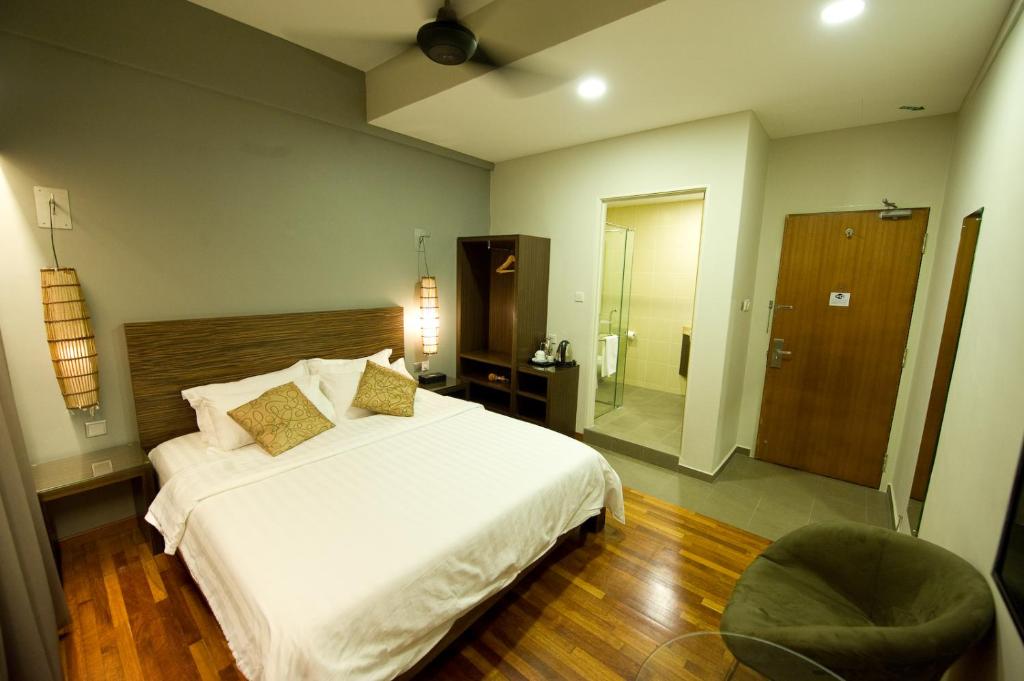 a bedroom with a large white bed and a chair at Riverside Boutique Hotel in Kuantan