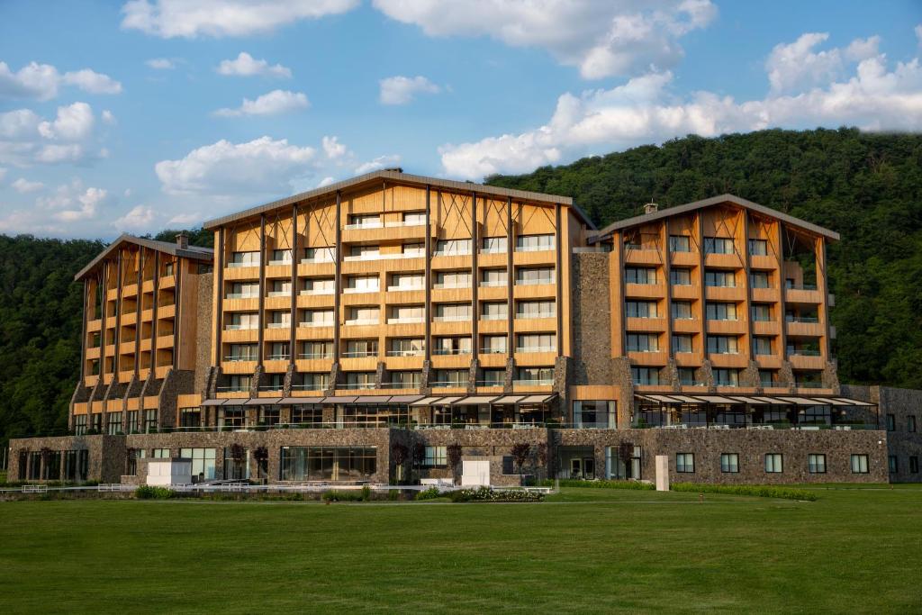 a large building with a grass field in front of it at Chenot Palace Gabala in Gabala