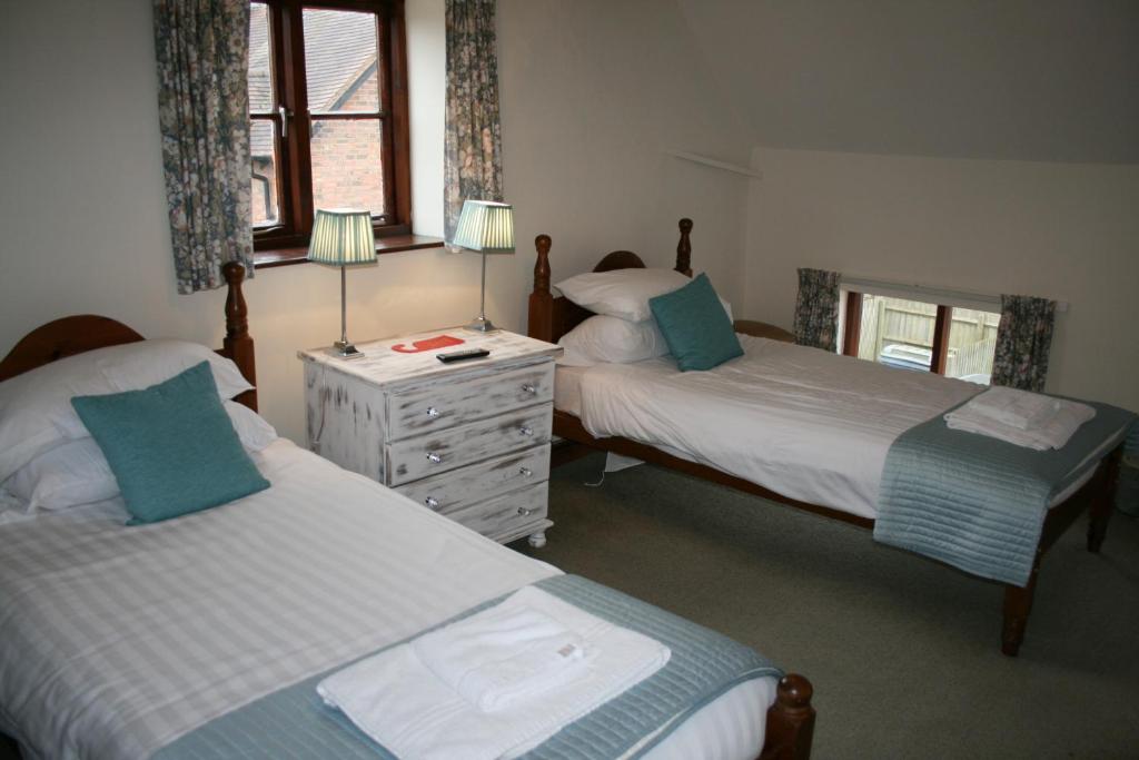 um quarto com 2 camas e uma cómoda com 2 candeeiros em The Talbot Inn em Much Wenlock
