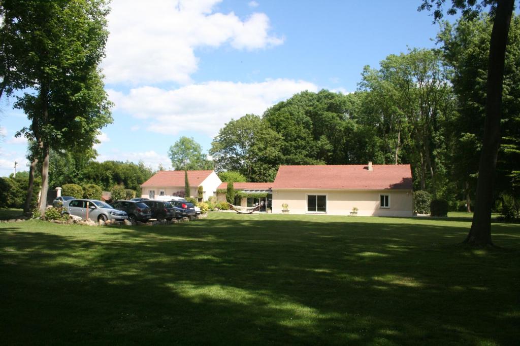 a house with cars parked in front of a yard at Maison au bout du chemin in Gouvieux