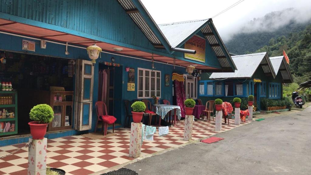 een blauw gebouw met tafels en stoelen op een geruite vloer bij Vamoose LIPPOHOCHHA HOMESTAY in Sombāri