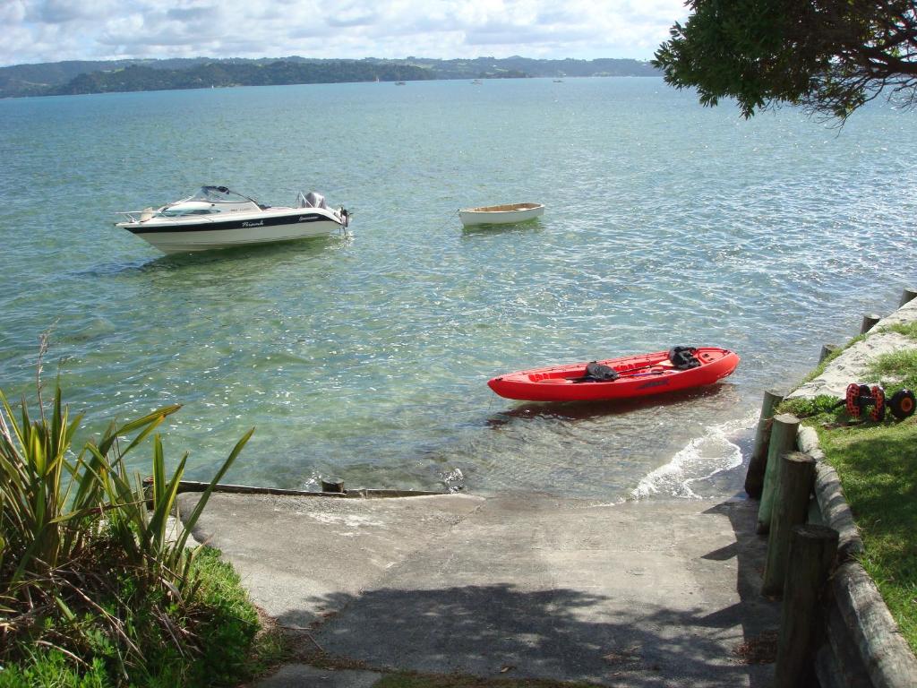 two boats in the water next to a dock at Harbourside Getaway in One Tree Point