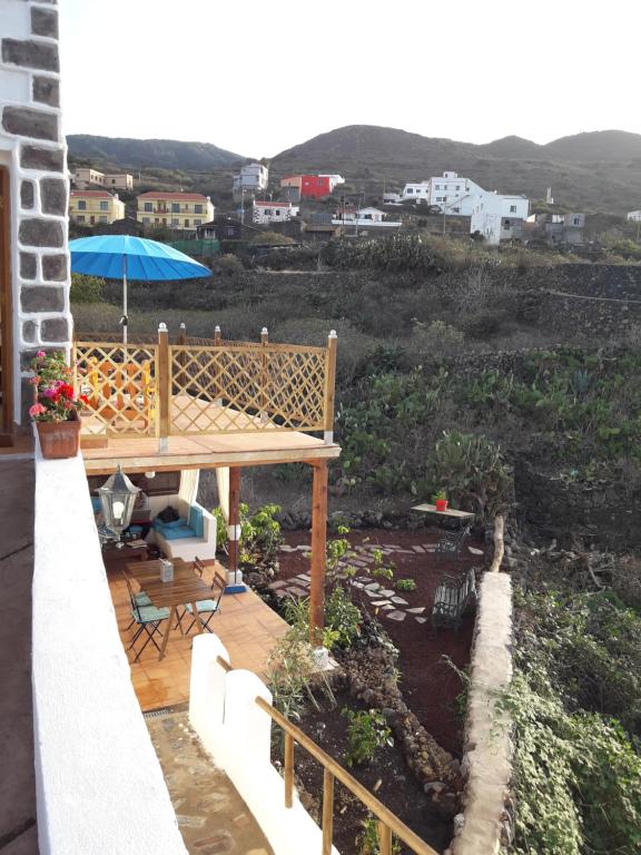 um pátio com um guarda-sol, uma mesa e cadeiras em Casa Rural SUNSET em Betenama