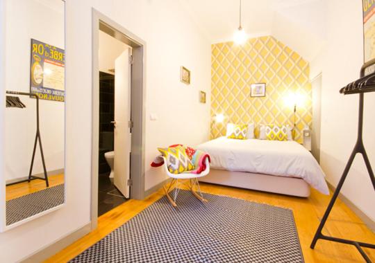um quarto com uma cama, uma cadeira e um espelho em Mouraria Deluxe Apartments em Lisboa