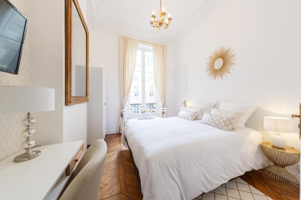 ein weißes Schlafzimmer mit einem großen Bett und einem Spiegel in der Unterkunft Maison de Lignières - Guest House - Paris quartier Champs-Elysées in Paris