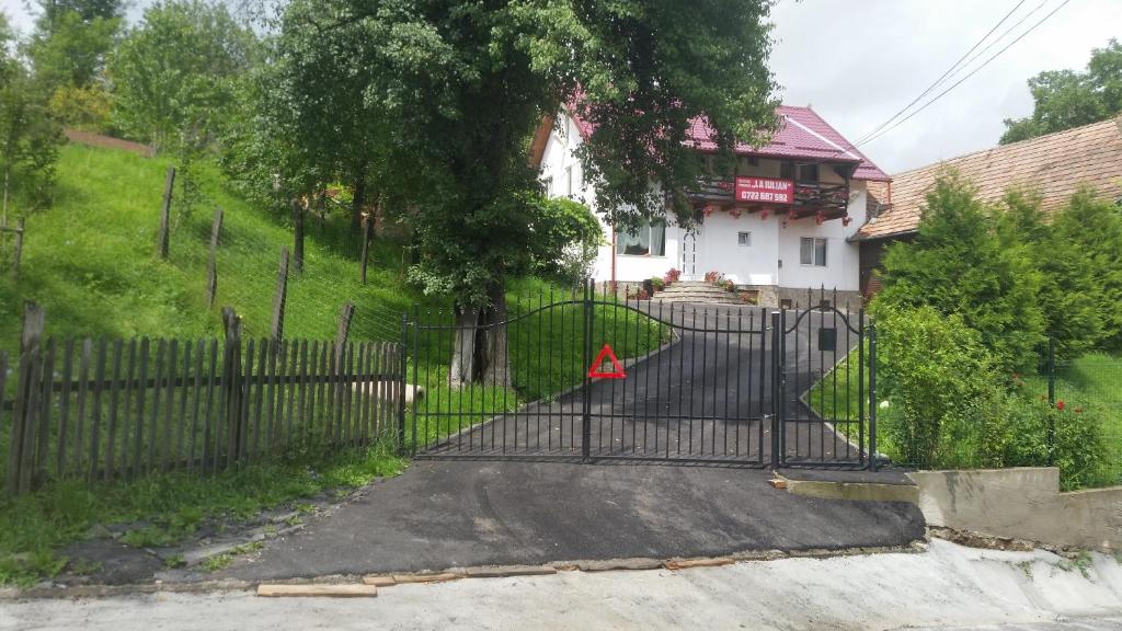 a gate with a triangle on it in front of a house at Pensiune La Iulian in Moieciu de Jos