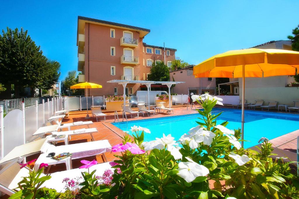 a swimming pool with lounge chairs and umbrellas at Residence I Girasoli in Rimini
