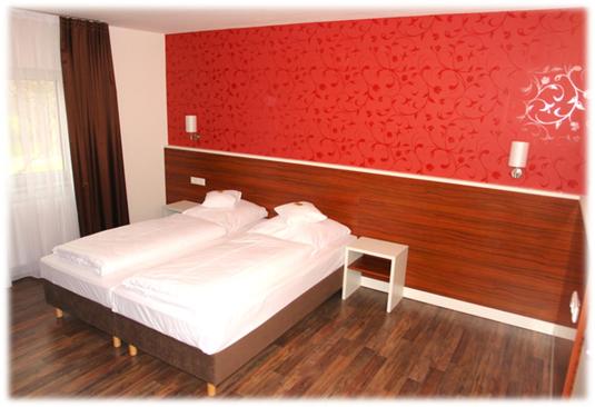 ネッカーズルムにあるBrau Art Hotelの白いベッドと赤い壁が備わるベッドルーム1室が備わります。