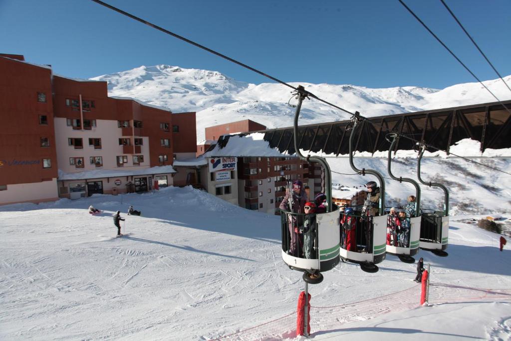 a group of people riding a ski lift in the snow at Résidence Le Chalet du Mont Vallon in Les Menuires
