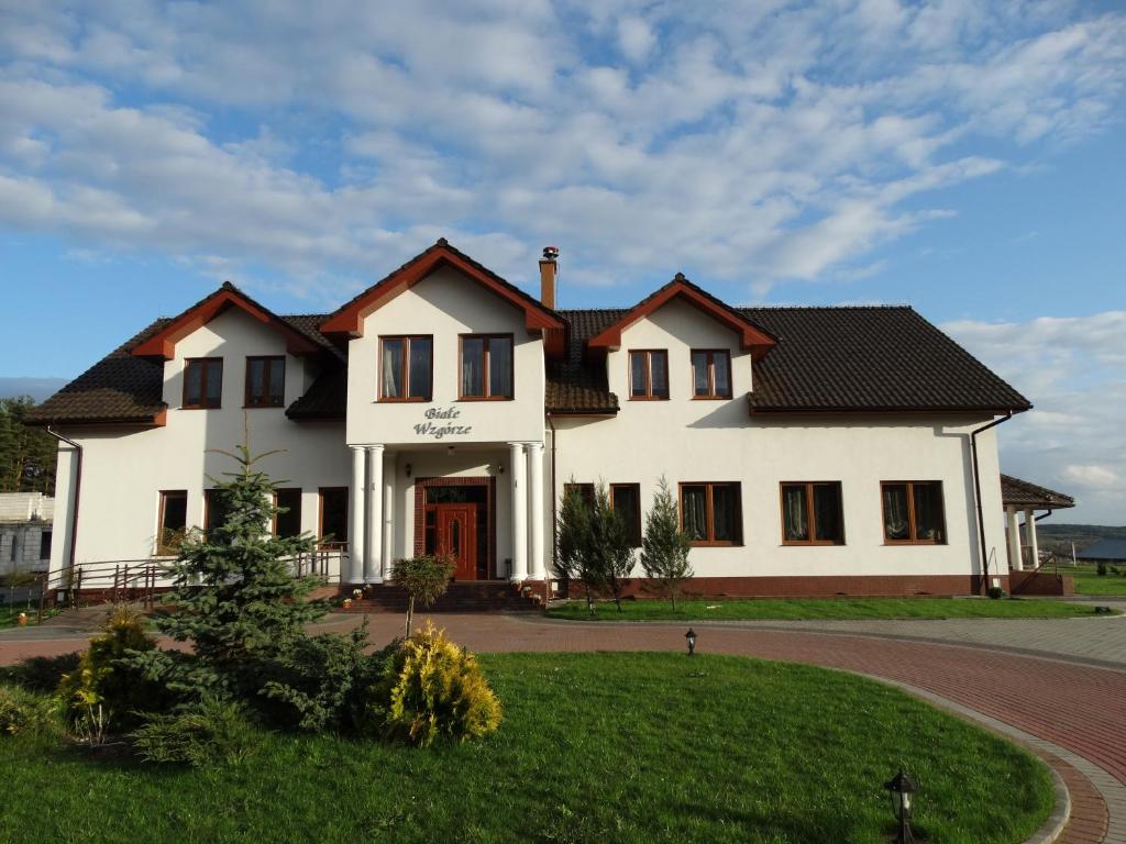 a large white house with a driveway at Białe Wzgórze in Okonek